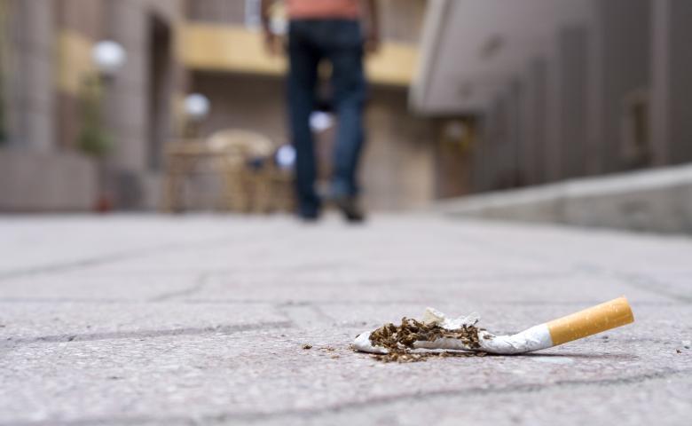 Man walking away from a cigarette put out on a sidewalk