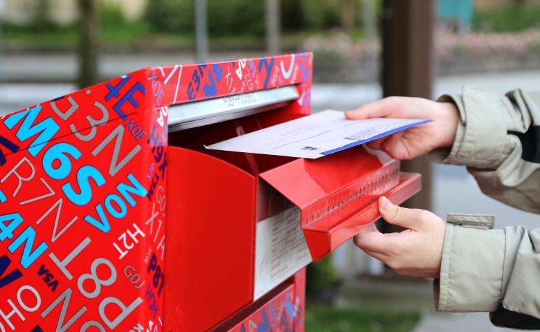 Person mailing a letter in a Canada Post mailbox