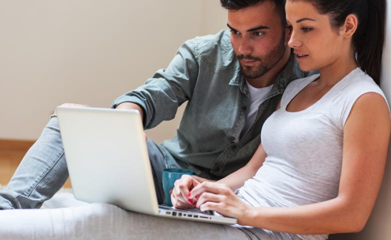 Couple sitting on floor and using laptop