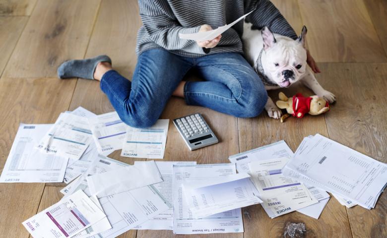 Woman sifting through receipt pile on the floor with her dog nearby