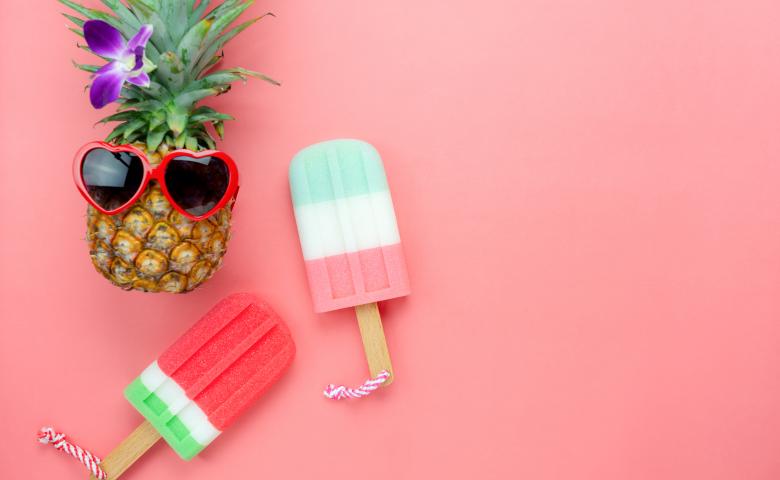 Pink background with pineapple wearing sunglasses and popsicles